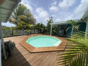 a swimming pool on a wooden deck next to a house at Papaye et coconut in Anse-Bertrand