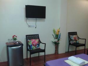 a living room with two chairs and a tv on the wall at Vhauschild Transient Rooms in Alaminos