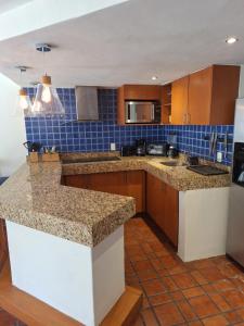 a kitchen with granite counter tops and wooden cabinets at Depa en planta baja con alberca in Puerto Vallarta
