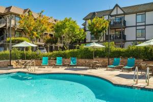 a swimming pool with chairs and umbrellas in front of some apartments at WorldMark Solvang in Solvang
