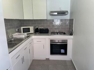 a kitchen with white cabinets and a sink and a microwave at Soleya Apartment in Quartier de Lorient