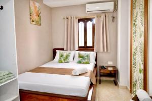 a bedroom with a bed with white sheets and green pillows at HOTEL LUA ORIGENEs in Rodadero