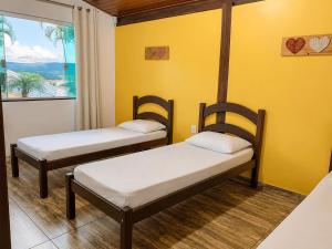 two beds in a room with a yellow wall at Casa com Vista inigualável "Vista del Lago" in Capitólio +14 photos