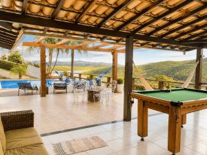 a patio with a pool table and a hammock at Casa com Vista inigualável "Vista del Lago" in Capitólio