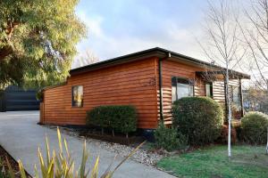 a small wooden cabin with a porch at Alpine Digs in Jindabyne