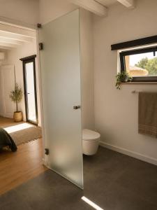 a bathroom with a toilet and a glass door at Recanto D Idjaro in Recanto +26 photos