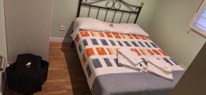 a bed with an orange and gray blanket on it at Casa Lyly in Quincoces de Yuso