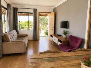a living room with a couch and a tv at Casa com Jacuzzi Charme Corumbá in Alexânia