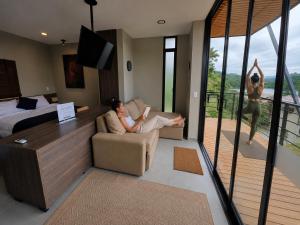 a woman sitting on a couch in a room with a balcony at Stella club & resort in Hacienda La Cabaña