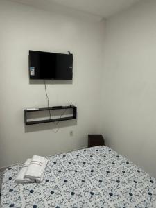 a bedroom with a bed with a tv on the wall at Estadia rápida- Quarto 3 in Bayeux