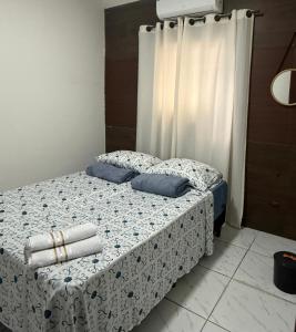 a bed with blue pillows and a curtain at Estadia rápida- Quarto 3 in Bayeux