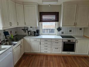 a kitchen with white cabinets and a sink and a window at Huset på øya in Vadsø