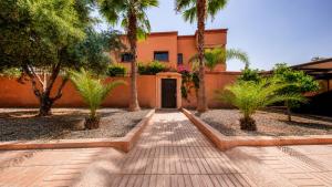 a house with palm trees in front of a walkway at Villa Amroth in Marrakesh