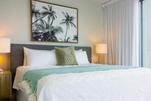 a bedroom with a large white bed with palm trees at 403 - Suva City Views Oceanfront Large Balcony in Suva