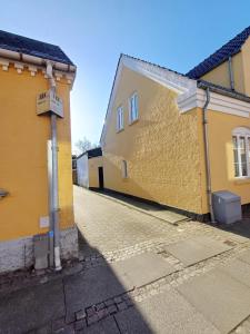 an alley between two yellow buildings with a street at Double room 1 with Free Parking in Nørresundby