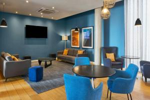 a living room with blue chairs and a table at Four Points Flex by Sheraton Cardiff in Cardiff