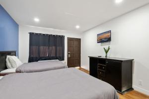 a bedroom with two beds and a desk and a window at Encore Inn Inglewood in Inglewood