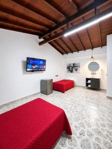 a bedroom with a red bed and a flat screen tv at Hotel Ofix - Laureles in Medellín