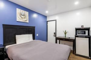 a bedroom with a bed and a blue wall at Encore Inn Inglewood in Inglewood