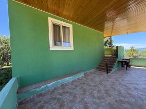 a green building with a window and stairs on it at Relax in mountains in İsmayıllı
