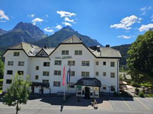 Ein großes weißes Gebäude vor dem Hintergrund der Berge in der Unterkunft Typically Swiss Hotel Altana in Scuol