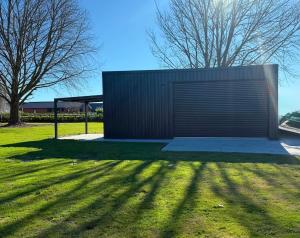 a building with a large door on a grass field at Pirongia Views Studio in Pirongia