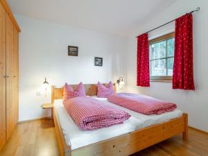 ein Schlafzimmer mit einem Bett mit roten Vorhängen und einem Fenster in der Unterkunft Schneeberghütte in Thiersee