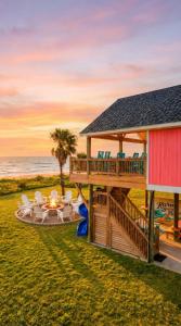 a house on the beach with a deck and chairs at Beachfront Luxe, Ocean Views, Hot tub, Firepit, Sleeps 14 in Bolivar Peninsula