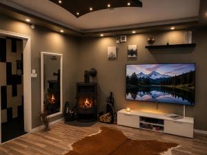 a living room with a large flat screen tv and a fireplace at Lägenhet med trädgård på Österlen, nära hav & golf in Gärsnäs