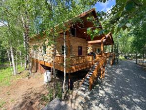 a log cabin with a deck in the woods at Riverfront, Authentic, Luxury Log Cabin-Gray Wolf in Wasilla