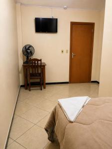 a room with a bed and a table and a flat screen tv at hotel Maanaim in Candói +21 photos