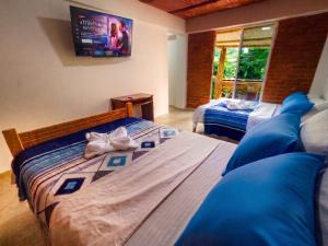 a bedroom with two beds and a tv on the wall at ISA BELLA Hospedaje y Cabaña Entre Aves in Luna Park