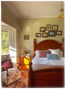 a bedroom with a bed and a chair and a window at Waterfront Casilda Guesthouse in Dunalley