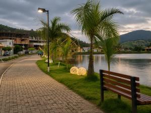 a park bench next to a river with palm trees at Flat com Jacuzzi em Capitólio - Cantinho do Lago 1 in Capitólio