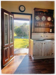 an open door to a kitchen with a clock on the wall at Waterfront Casilda Guesthouse in Dunalley