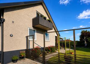 a house with a balcony with flowers on it at Lägenhet med trädgård på Österlen, nära hav & golf in Gärsnäs