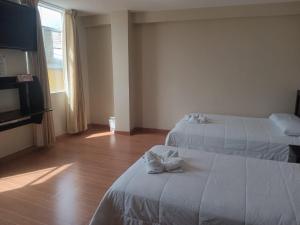 a hotel room with two beds and a flat screen tv at Paskary Hotel in Cajamarca