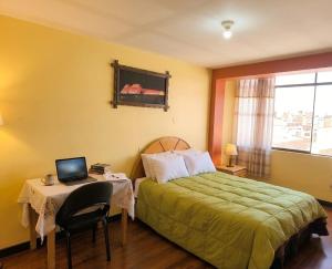 a bedroom with a bed and a desk with a laptop at Andenes Perú in Puno