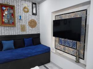 a living room with a blue couch and a flat screen tv at House Near the Sky in Dar Salah Bey