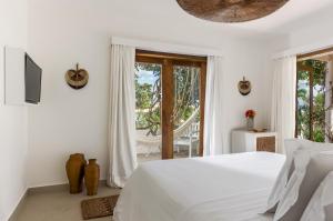 a white bedroom with a bed and a balcony at Villa Praia - La Villa Group in Jericoacoara
