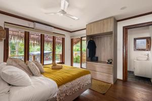 a bedroom with a large bed with a yellow blanket at Marbella Mentawai Beachfront Private Villa Sleeps 10 in Katiet