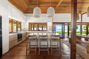 a kitchen with wooden ceilings and a table with chairs at Marbella Mentawai Beachfront Private Villa Sleeps 10 in Katiet