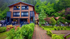 a large wooden house with a walkway in front of it at Akyuz Kardesler Hotel & Bungalow in Uzungöl