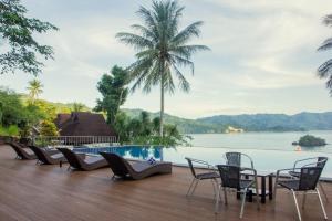 a deck with chairs and a pool and water at Chads Dive Resort Lembeh in Bitung