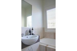 a bathroom with a sink and a tub and a mirror at Relax and Unwind with Private Hot Tub in Rosebud in Rosebud