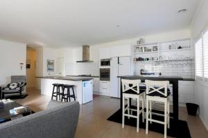 a kitchen with white cabinets and a bar with stools at Relax and Unwind with Private Hot Tub in Rosebud in Rosebud +10 photos