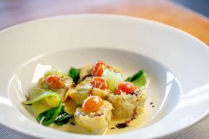 a white bowl of food with vegetables on a table at Chads Dive Resort Lembeh in Bitung