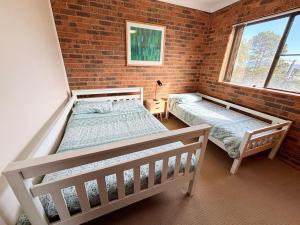 a bedroom with two beds and a brick wall at Seaview Townhouse 2 - Bring your own linen. in South West Rocks