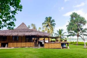 a house with a thatched roof and a table at Marbella Mentawai Beachfront Private Villa Sleeps 10 in Katiet