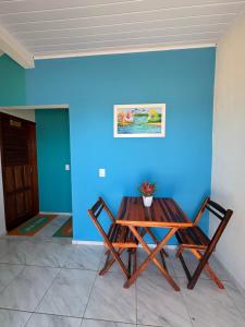 Ein Tisch und zwei Stühle neben einer blauen Wand in der Unterkunft Chalés do mar in Icapuí